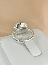 Load image into Gallery viewer, A polished sterling silver back ring with a rose head on top of a white display cushion against a soft beige background.
