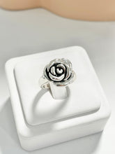 Load image into Gallery viewer, A silver 925 ring shaped like a rose, displayed on a white square jewelry stand against a light gray background.
