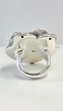 Load image into Gallery viewer, A sterling silver ring shaped like a stylized flower with a thick, polished band, photographed on a clean white surface with a light gray background.
