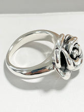 Load image into Gallery viewer, A polished sterling silver ring featuring a sculpted rose motif on the band, photographed on a clean white surface with a soft shadow.
